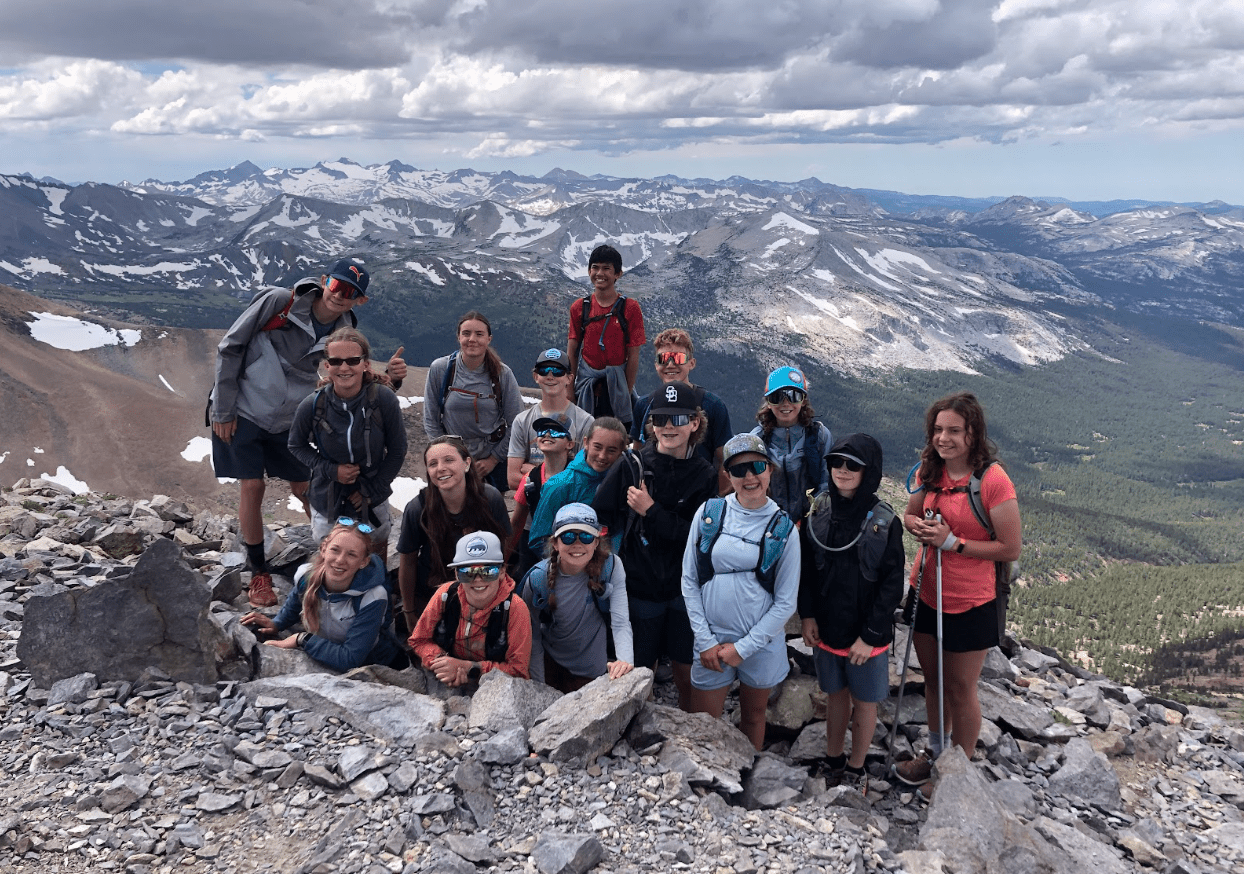 Group of smiling people on top of a mountain